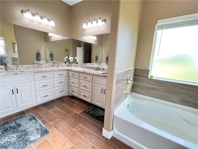 bathroom with a washtub, vanity, and wood-type flooring