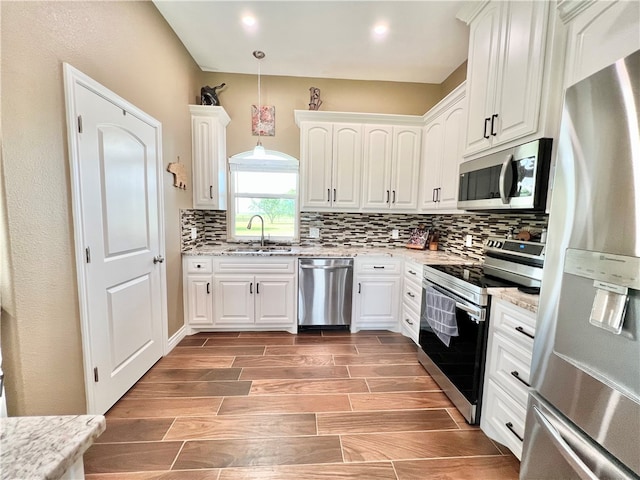 kitchen with white cabinets, pendant lighting, stainless steel appliances, and sink