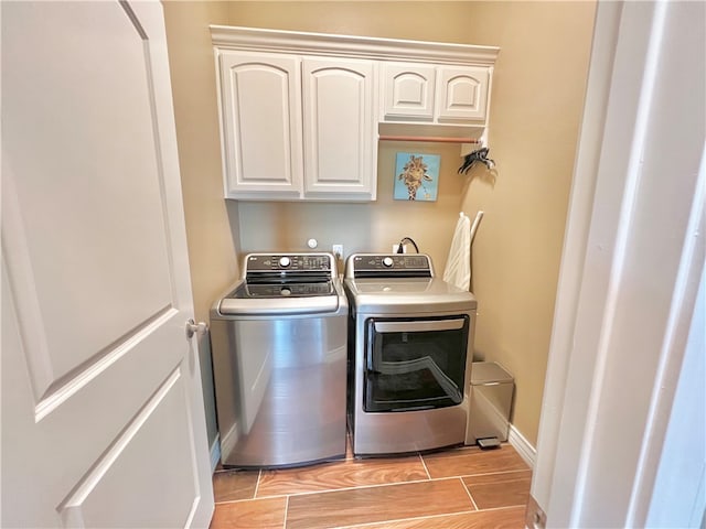 clothes washing area with washer and dryer, cabinets, and light wood-type flooring