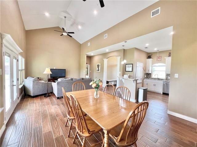 dining area featuring decorative columns, ceiling fan, high vaulted ceiling, and hardwood / wood-style flooring