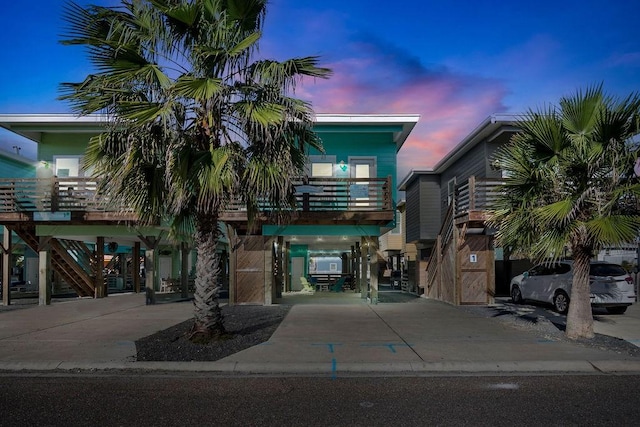 view of property with a carport, driveway, and stairway