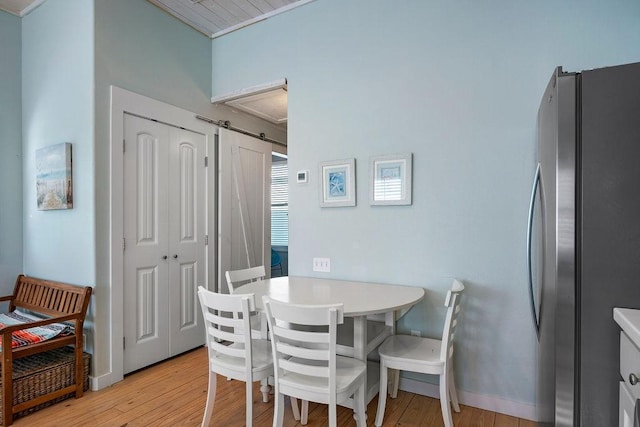 dining space featuring light wood-type flooring, baseboards, and a barn door