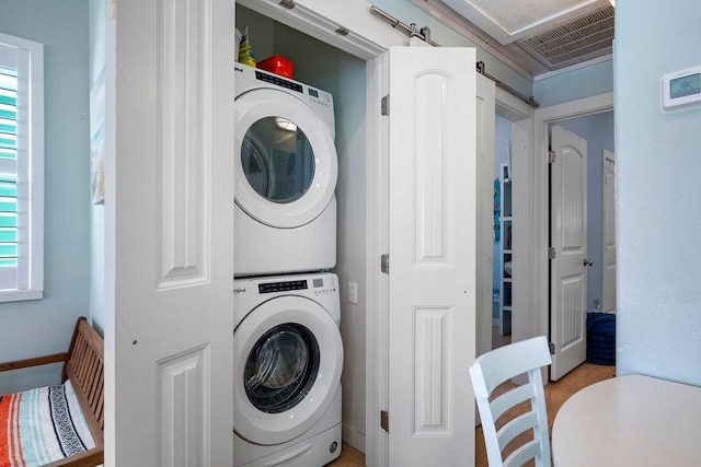 laundry room featuring laundry area, a barn door, visible vents, baseboards, and stacked washer and clothes dryer