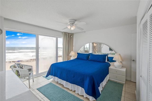 14810 Windward Dr Unit 509, Corpus Christi, TX 78418 - bedroom with a water view, a textured ceiling, a ceiling fan, and tile patterned flooring