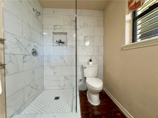 bathroom featuring toilet, tiled shower, and tile patterned floors