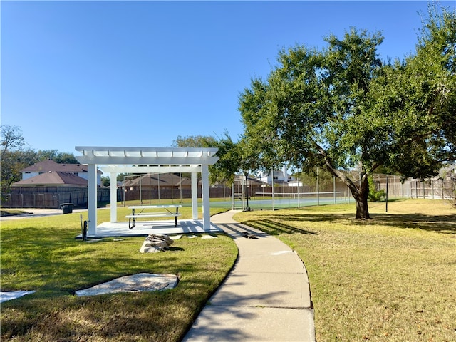 view of property's community with a pergola, a lawn, and tennis court