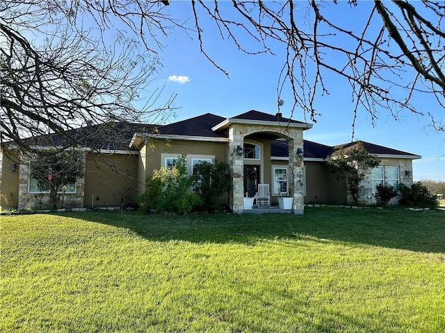 view of front facade with stucco siding, stone siding, and a front yard