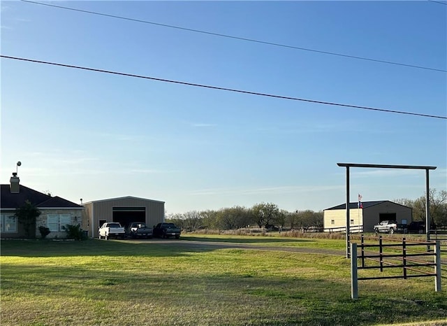 view of yard featuring a garage, an outbuilding, and fence