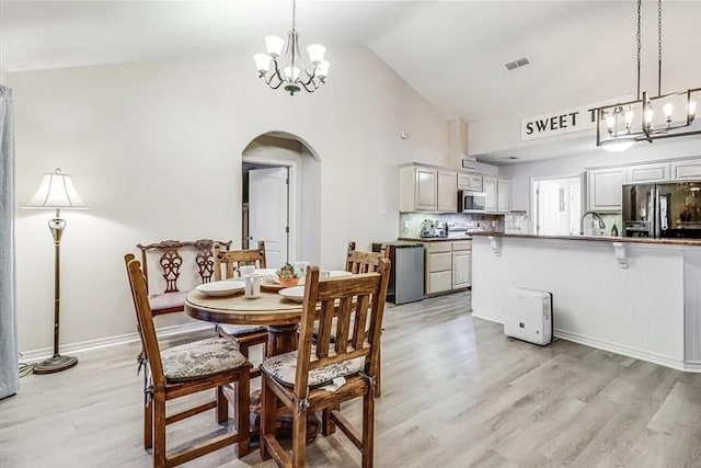 14877 Cobo De Bara, Corpus Christi, TX 78418 - dining room featuring a chandelier, arched walkways, light wood finished floors, and high vaulted ceiling