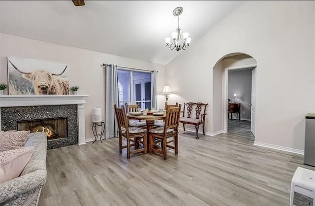 14877 Cobo De Bara, Corpus Christi, TX 78418 - dining space featuring arched walkways, light wood-style floors, a chandelier, high vaulted ceiling, and a tile fireplace