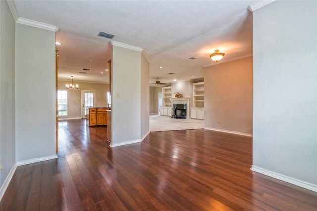 unfurnished living room with ceiling fan with notable chandelier, dark hardwood / wood-style floors, built in features, and crown molding