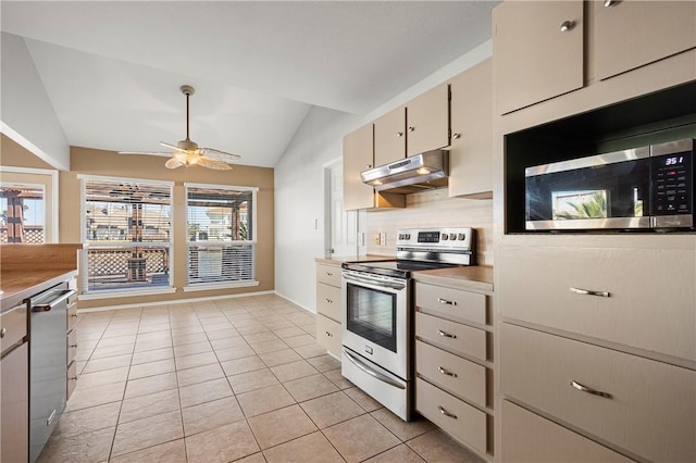 kitchen with under cabinet range hood, lofted ceiling, light tile patterned floors, decorative backsplash, and stainless steel appliances