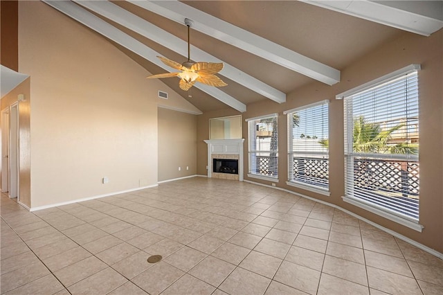 unfurnished living room featuring light tile patterned floors, a ceiling fan, baseboards, a tiled fireplace, and beamed ceiling