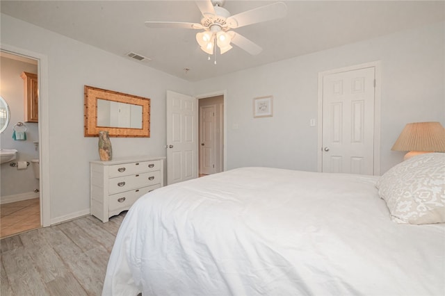 bedroom featuring light wood-type flooring, ceiling fan, and ensuite bath