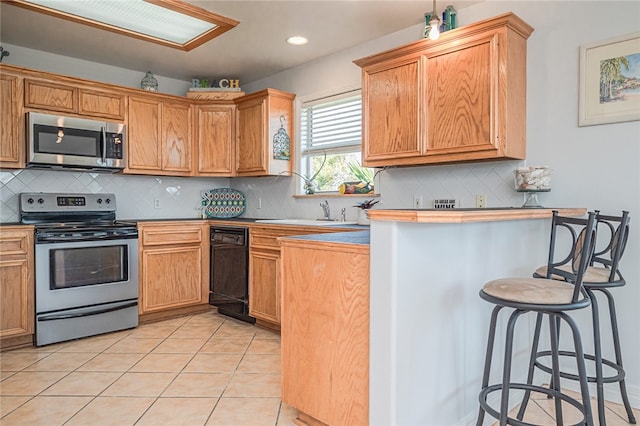 kitchen featuring backsplash, light tile patterned floors, a breakfast bar, and appliances with stainless steel finishes