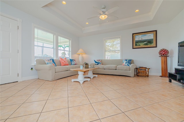 tiled living room with ornamental molding, ceiling fan, and a raised ceiling