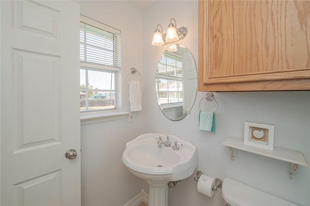 bathroom with toilet, sink, and a healthy amount of sunlight