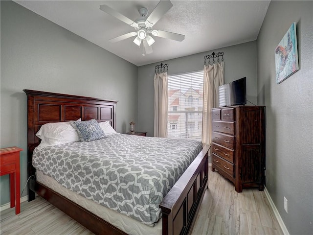 bedroom with a ceiling fan, light wood-style flooring, and baseboards