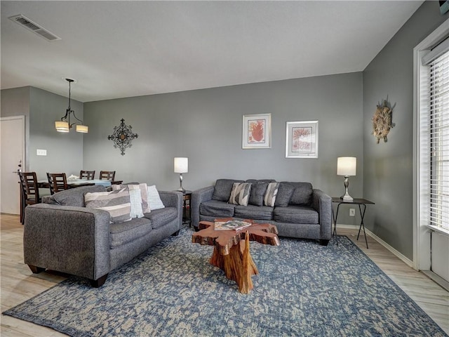 living room featuring baseboards, light wood-style flooring, visible vents, and a wealth of natural light