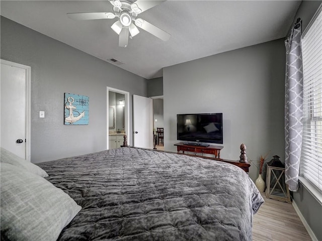 bedroom with light wood finished floors, visible vents, ensuite bathroom, ceiling fan, and baseboards