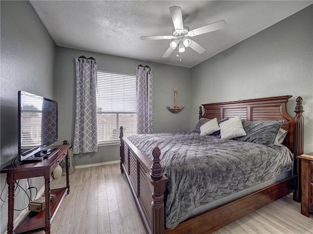 bedroom with a ceiling fan, baseboards, a textured ceiling, and light wood finished floors