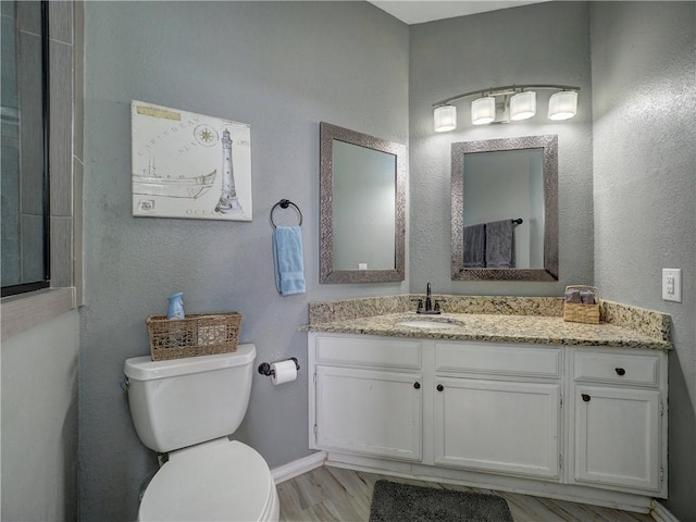 full bathroom with baseboards, vanity, toilet, and wood finished floors