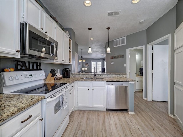 kitchen featuring pendant lighting, visible vents, appliances with stainless steel finishes, white cabinetry, and a sink