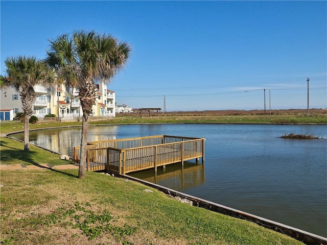 view of dock with a yard and a water view