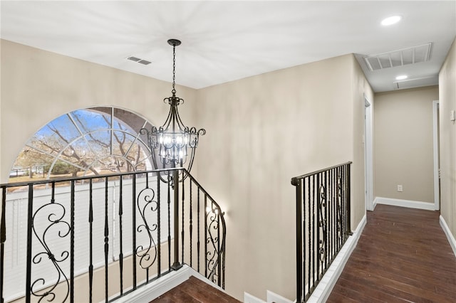 staircase with visible vents, wood finished floors, an inviting chandelier, and attic access