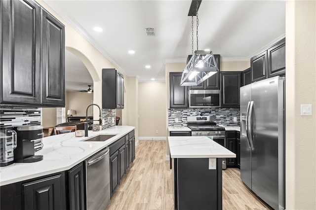 kitchen with crown molding, appliances with stainless steel finishes, dark cabinetry, and a sink