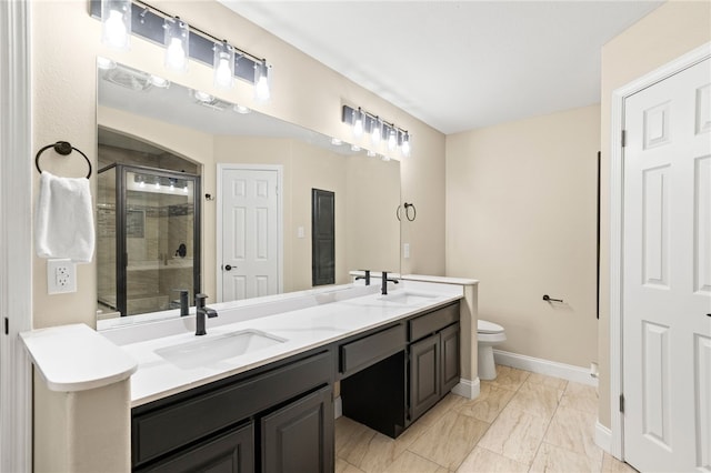 bathroom featuring a shower stall, toilet, double vanity, and a sink