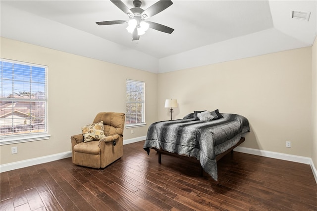 bedroom featuring visible vents, a raised ceiling, baseboards, and wood finished floors