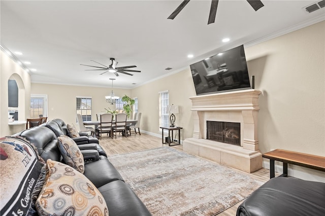 living area with ornamental molding, wood finished floors, visible vents, and ceiling fan