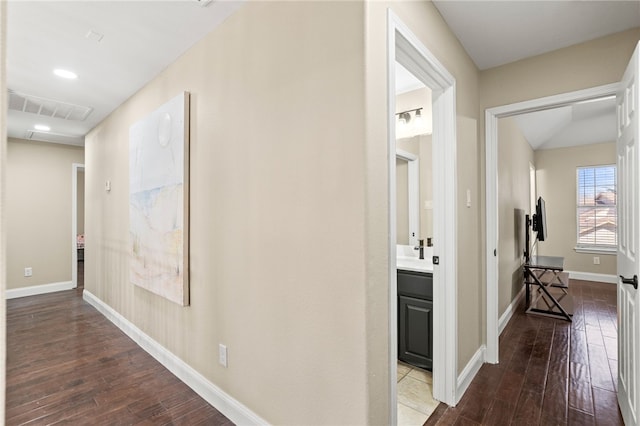 corridor with visible vents, baseboards, and hardwood / wood-style floors