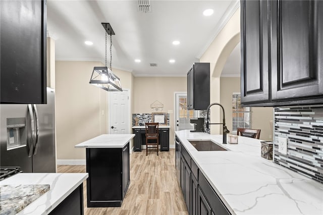 kitchen featuring a sink, arched walkways, dark cabinets, and stainless steel refrigerator with ice dispenser