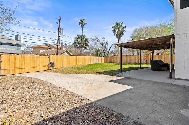 view of yard featuring a fenced backyard, concrete driveway, and a patio