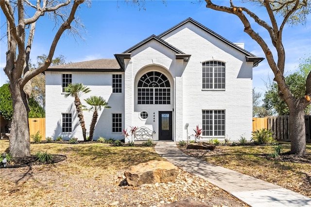 traditional-style home featuring brick siding and fence