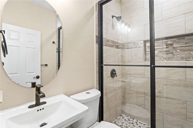 full bathroom with a sink, toilet, a stall shower, and a textured wall