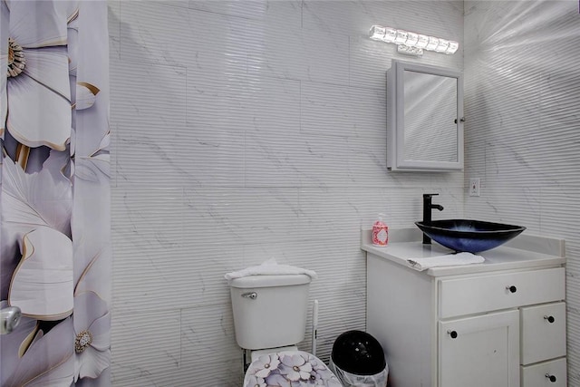 bathroom featuring vanity, tile walls, and toilet