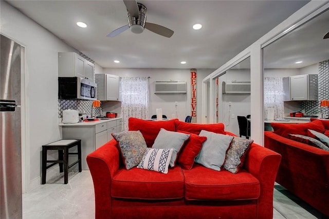 living room with an AC wall unit and ceiling fan