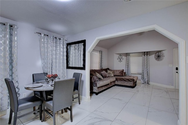 dining room with a textured ceiling and lofted ceiling