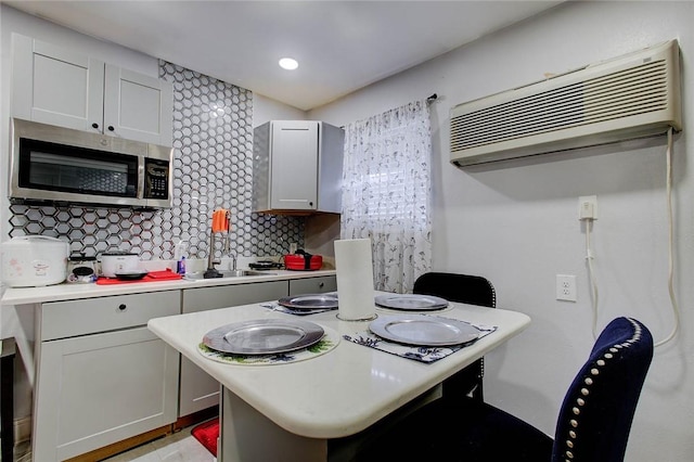 kitchen featuring decorative backsplash, a wall mounted air conditioner, gray cabinetry, and sink