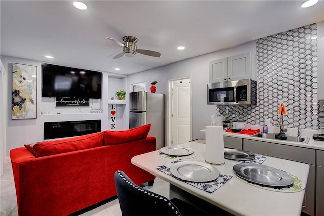 kitchen featuring decorative backsplash, ceiling fan, light tile patterned floors, appliances with stainless steel finishes, and white cabinetry