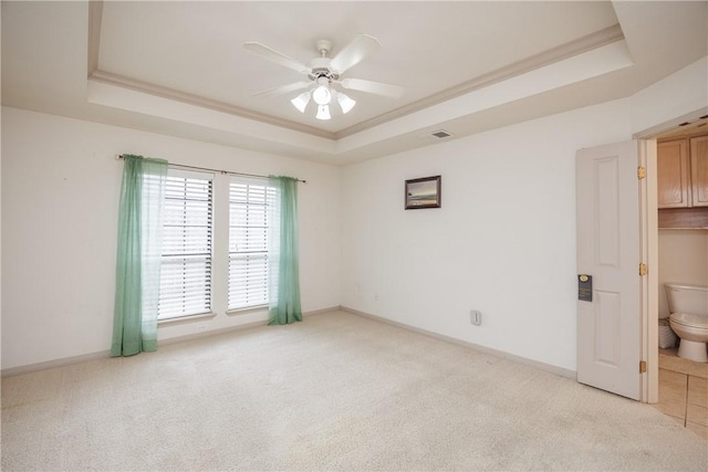 unfurnished room featuring baseboards, a raised ceiling, and light colored carpet