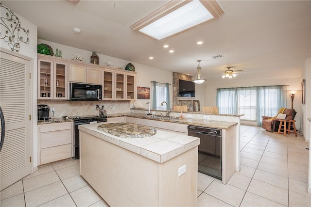 kitchen with light countertops, glass insert cabinets, a kitchen island, a peninsula, and black appliances