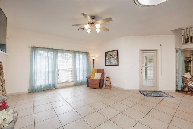 living area featuring light tile patterned floors, ceiling fan, visible vents, and baseboards