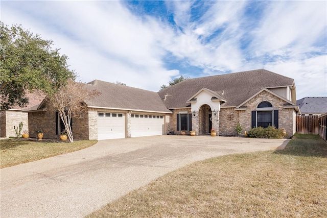 view of front of home featuring driveway, an attached garage, fence, and a front lawn