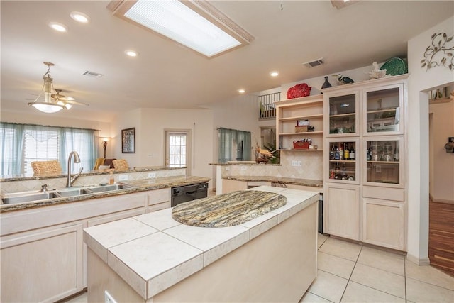 kitchen featuring a peninsula, light countertops, dishwasher, and a center island