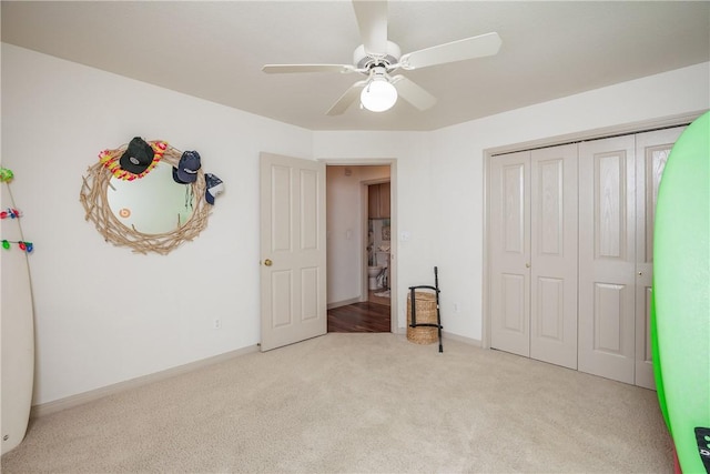 unfurnished bedroom featuring light carpet, ceiling fan, baseboards, and a closet