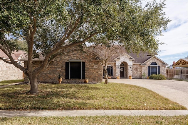 view of front of property featuring driveway, a front lawn, fence, and brick siding